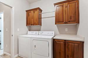 Washroom featuring separate washer and dryer, cabinets, and light tile patterned flooring