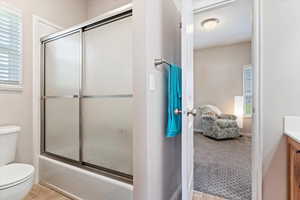 Full bathroom with vanity, tile patterned flooring, shower / bath combination with glass door, and toilet