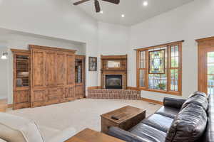 Family room with a high ceiling, a fireplace, carpet, and ceiling fan