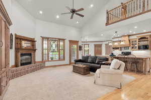 Family room with light carpet, a brick fireplace, high vaulted ceiling, and plenty of natural light