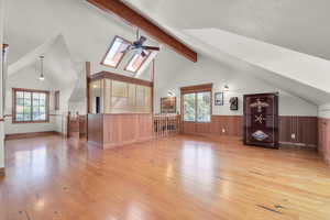 Additional living space featuring vaulted ceiling with skylight, wood flooring