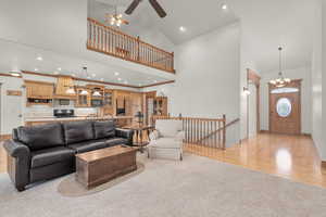 Family room with high vaulted ceiling, ceiling fan with notable chandelier, light hardwood / wood-style flooring, and ornamental molding