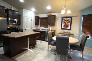 Kitchen with dark brown cabinets, stainless steel appliances, and light tile patterned floors