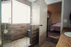 Bathroom featuring a shower, vanity, tile walls, and tile patterned floors