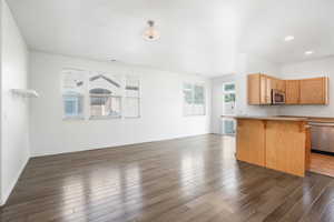 Kitchen with dark wood-type flooring, a kitchen breakfast bar, and stainless steel appliances