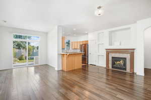 Unfurnished living room with a tile fireplace, a healthy amount of sunlight, and hardwood / wood-style flooring