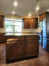 Kitchen featuring appliances with stainless steel finishes, a center island, and dark tile patterned flooring