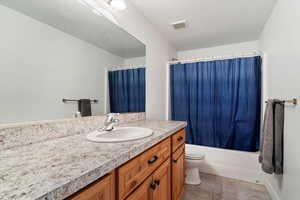 Full bathroom featuring tile patterned floors, shower / bath combo, toilet, and vanity