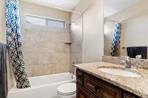 Full bathroom featuring vanity, shower / bath combo with shower curtain, and toilet