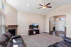 Living room with high vaulted ceiling, a fireplace, dark hardwood / wood-style floors, and ceiling fan