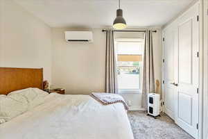 Carpeted bedroom featuring a wall unit AC and a textured ceiling