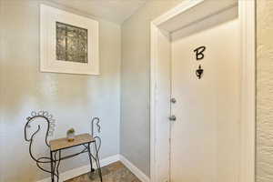 Doorway with tile patterned flooring and a textured ceiling