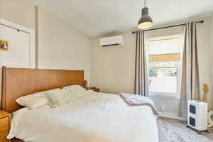 Carpeted bedroom featuring a wall mounted air conditioner