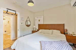 Bedroom with a wall mounted AC and light tile patterned floors