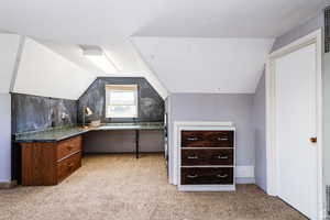 Interior space featuring vaulted ceiling and light colored carpet