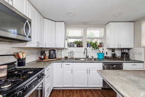 Kitchen with sink, appliances with stainless steel finishes, decorative backsplash, and dark hardwood / wood-style floors