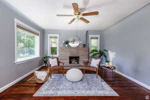 Sitting room with dark wood-type flooring, a fireplace, and ceiling fan