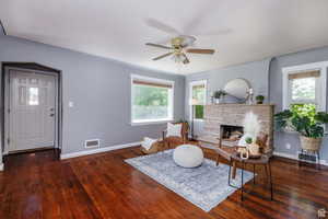 Living room featuring dark hardwood / wood-style flooring, a brick fireplace, and ceiling fan