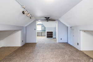 Additional living space with light carpet, vaulted ceiling, and ceiling fan