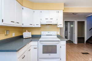 Kitchen featuring light hardwood / wood-style flooring, white electric range oven, and white cabinets