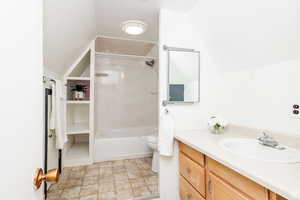 Full bathroom with shower / bath combination, lofted ceiling, tile patterned floors, toilet, and vanity