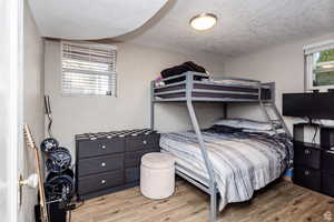 Bedroom with light hardwood / wood-style flooring and a textured ceiling