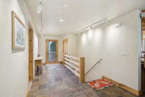 Corridor featuring dark tile patterned floors and track lighting