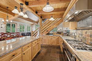 Kitchen featuring stainless steel appliances, beamed ceiling, decorative light fixtures, and backsplash