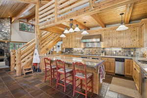 Kitchen featuring wall chimney range hood, a center island, beamed ceiling, and dark tile patterned floors