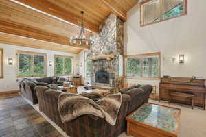 Tiled living room featuring an inviting chandelier, a fireplace, wooden ceiling, and vaulted ceiling with beams