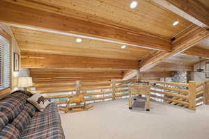 Interior space with carpet floors, wood ceiling, log walls, and ceiling fan