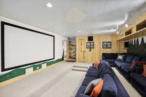 Carpeted home theater room with wood walls