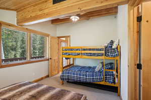 Bedroom with beamed ceiling, carpet floors, and ceiling fan