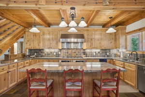 Kitchen with beam ceiling, decorative backsplash, dark tile patterned flooring, and wall chimney exhaust hood