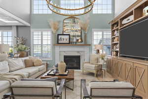 Living room with a towering ceiling, a high end fireplace, a chandelier, and plenty of natural light