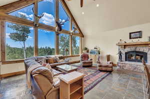 Living room with a fireplace, ceiling fan, plenty of natural light, and tile patterned flooring