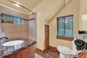 Bathroom featuring lofted ceiling, tile patterned floors, toilet, and vanity