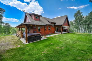 Rear view of property with a patio, a yard, and a hot tub