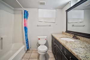 Basement Full bathroom with tile patterned flooring, a textured ceiling, toilet, shower / tub combo with curtain, and vanity