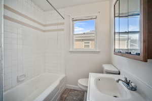 Full bathroom featuring tile patterned floors, sink, tiled shower / bath combo, and toilet