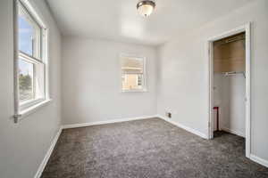 Unfurnished bedroom with a closet and dark carpet