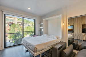 Bedroom with multiple windows, wood-type flooring, and access to outside