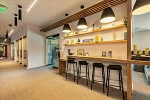 Bar featuring light carpet, pendant lighting, and wood counters