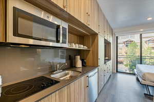 Kitchen with stainless steel appliances, light brown cabinetry, and sink