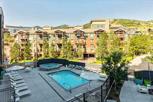 View of swimming pool with a patio and a hot tub