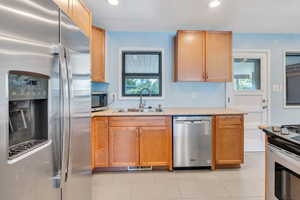 Kitchen featuring light tile patterned floors, appliances with stainless steel finishes, and sink