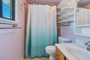 Bathroom featuring tile patterned floors, a shower with shower curtain, vanity, and toilet