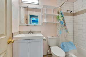 Full bathroom with shower / bath combination with curtain, toilet, and vanity