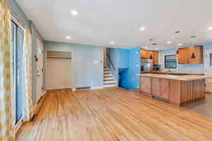 Kitchen featuring sink, appliances with stainless steel finishes, light hardwood / wood-style floors, a kitchen island, and hanging light fixtures