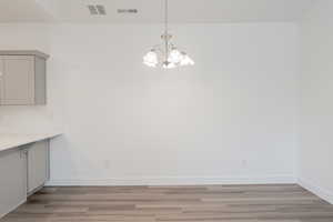 Unfurnished dining area featuring light wood-type flooring and a notable chandelier